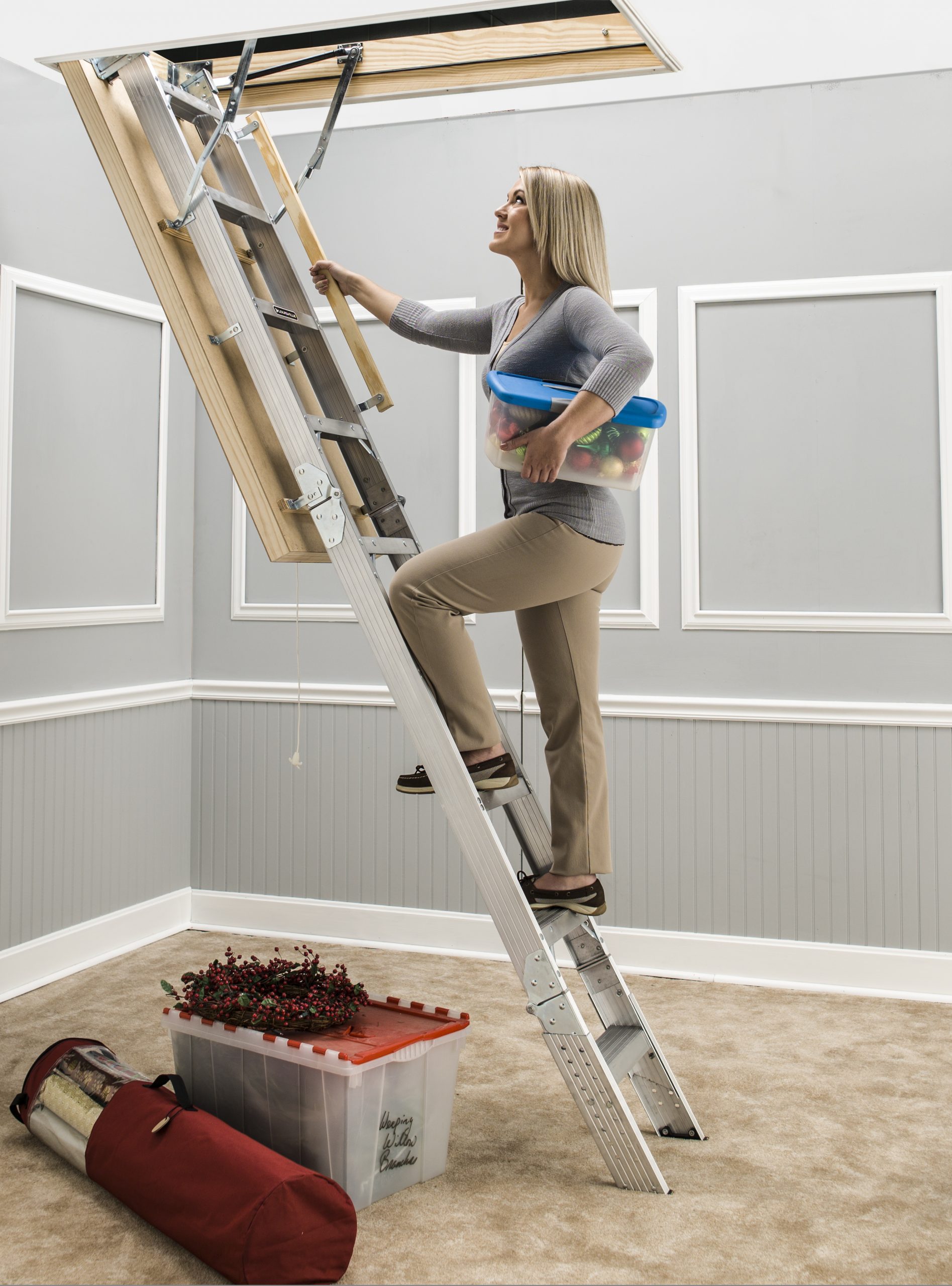 A women standing on a ladder leading up to an attic.